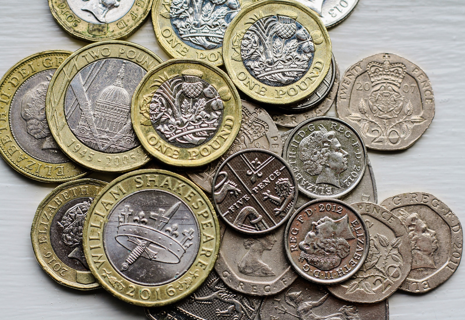 a pile of british coins sitting on top of a table